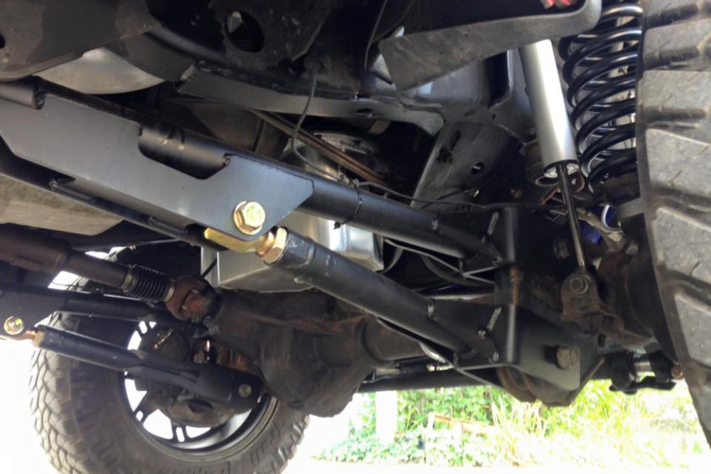 Death Wobble in Diesel Trucks, Diesel Repair Shop in Bremen,OH. Image of a vehicle’s undercarriage showing upgraded control arms, heavy-duty links, coil springs, and shock absorbers designed for improved off-road performance and stability.