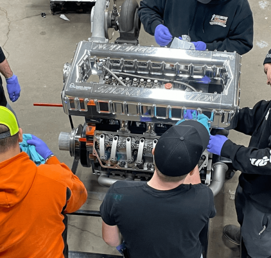 diesel performance upgrades, diesel repair in Bremen, OH at Unlimited Diesel Performance. Team assembling a high-performance engine at an auto shop, focusing on precision and collaboration.